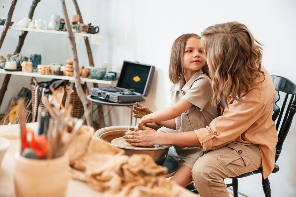 Creative process. Mother with little girl doing pottery at home.