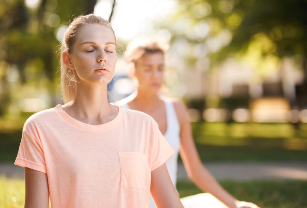 Women doing yoga outdoors at sunrise. Morning meditation.
